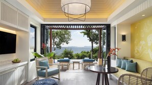 Un salón moderno con un televisor grande, asientos cómodos, una mesa de comedor y vistas al mar.