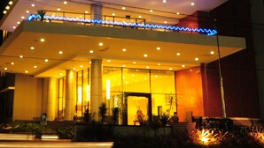 Un hotel moderno con una entrada destacada, varios pisos y una torre distintiva con el nombre 'STON'.