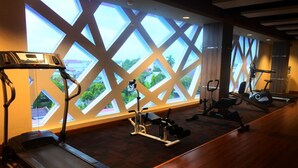 Un gimnasio con equipamiento de ejercicio, ventanas amplias y suelo de madera.