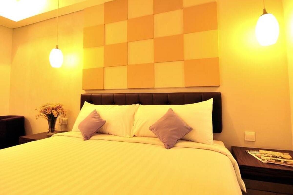 A hotel room with a bed, a nightstand, a lamp, and a wall with a geometric pattern.