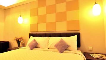 A hotel room with a bed, a nightstand, a lamp, and a wall with a geometric pattern.