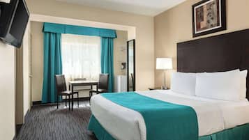 Une chambre d’hôtel avec un lit, un bureau, une chaise, une télévision et un tableau au mur.