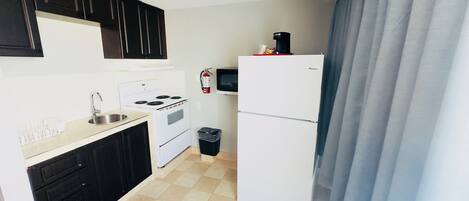 Una cocina compacta con estufa, lavamanos y refrigerador.