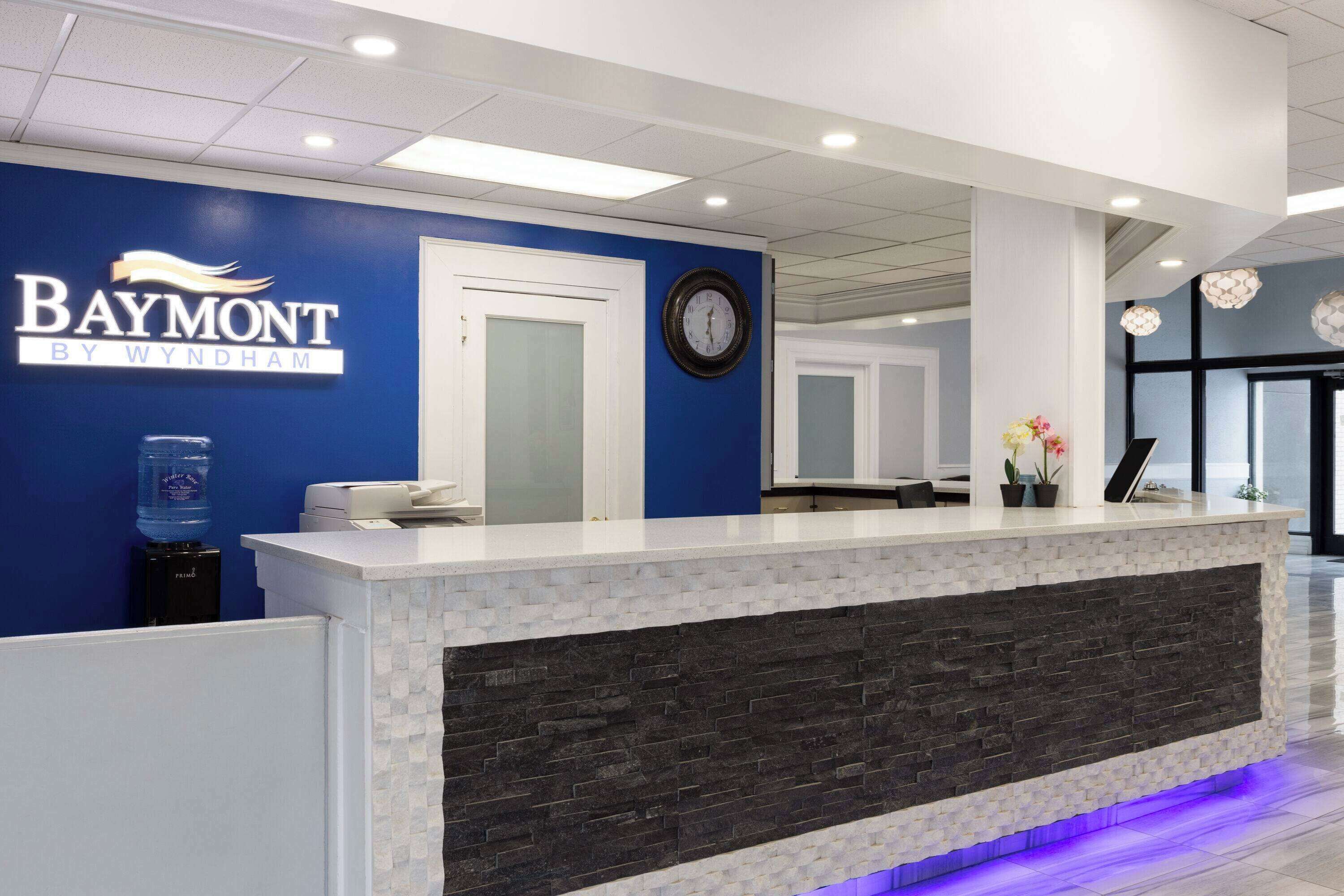 A reception desk with a blue wall, a clock, and a water dispenser.