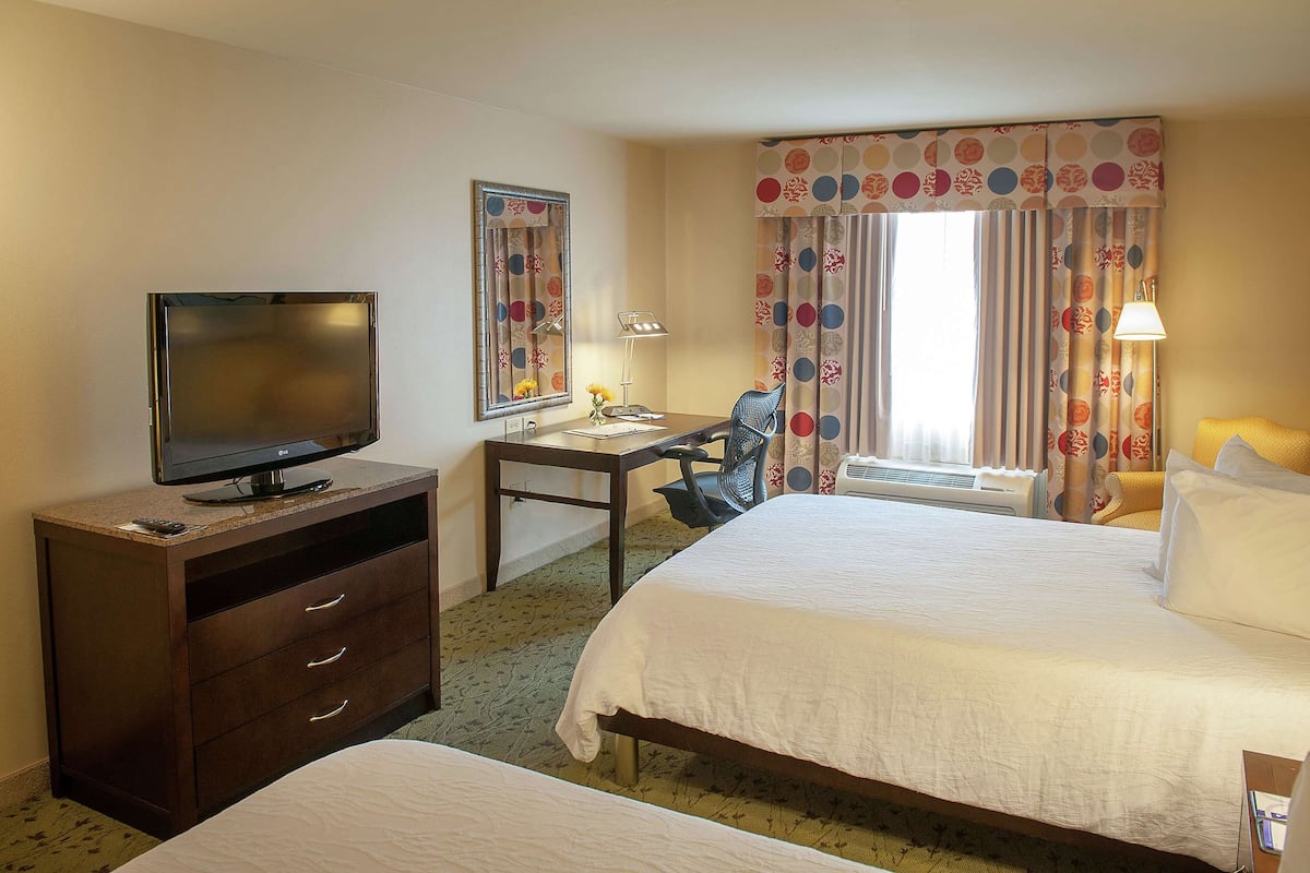 A hotel room with a bed, a desk with a computer, a television, and a chair.