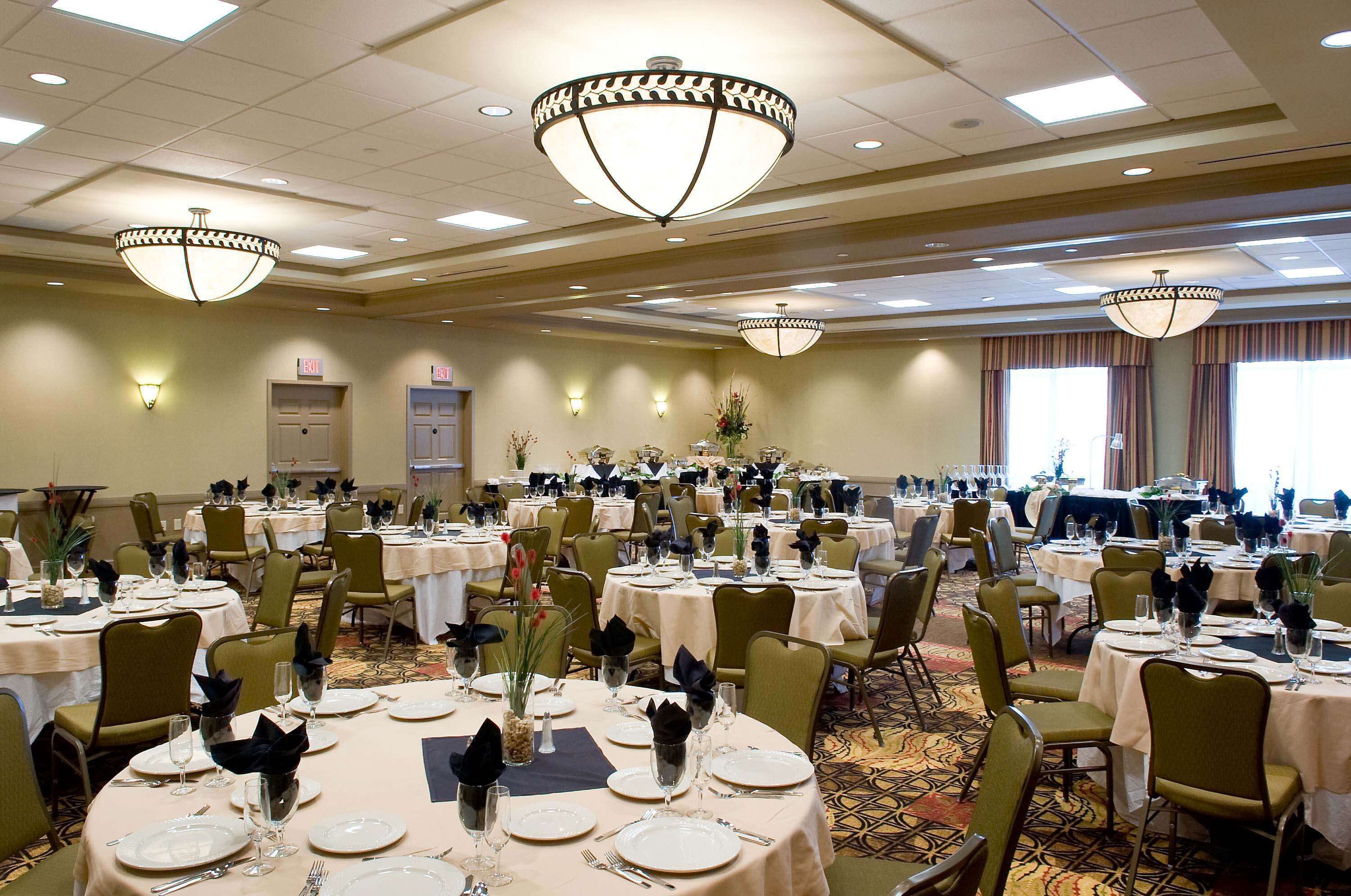 A banquet hall with round tables set for dining, equipped with chairs and table settings.
