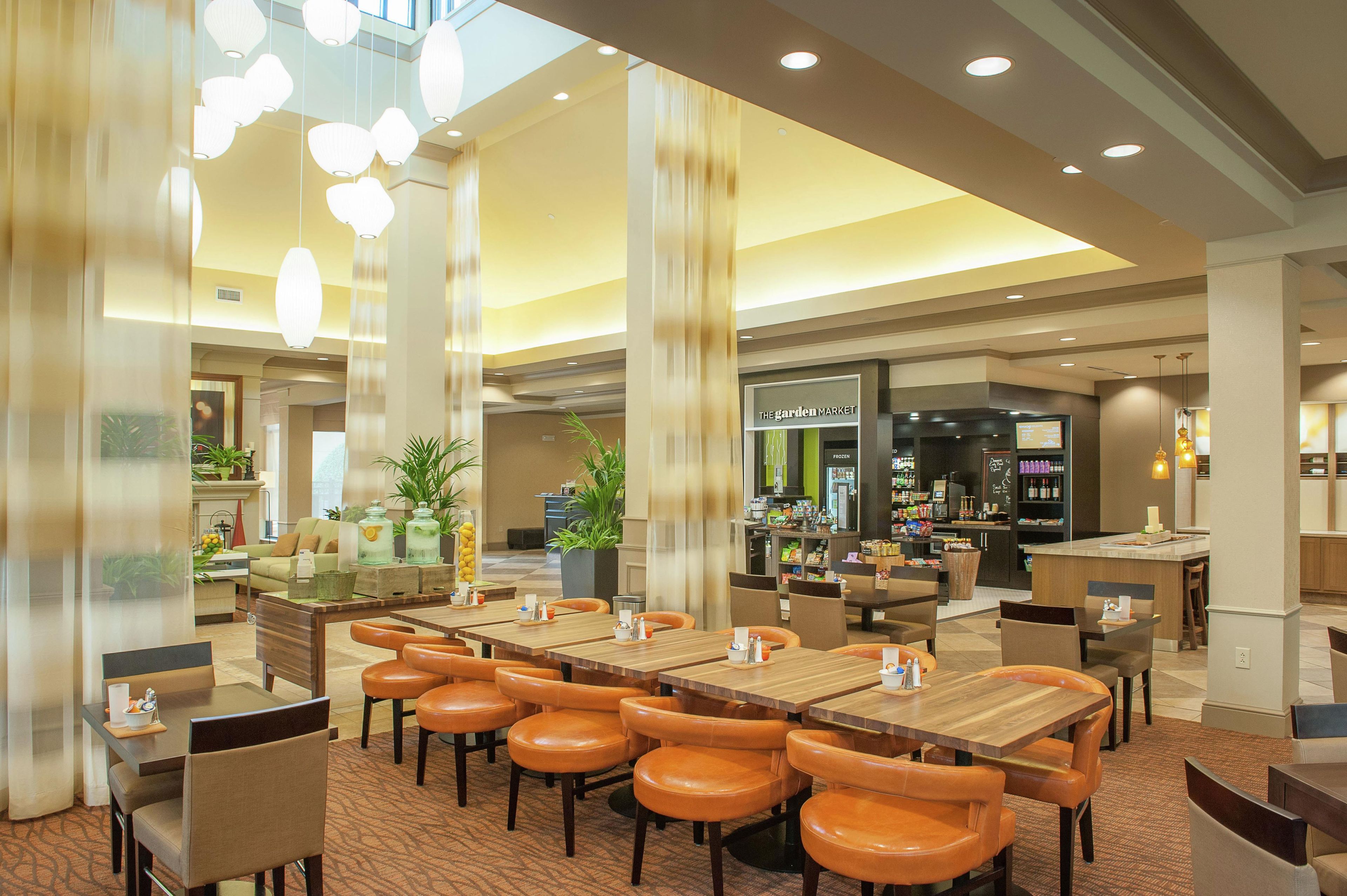 Un hall de hotel espacioso con varias zonas de estar, incluyendo un bar y una sección de comedor.