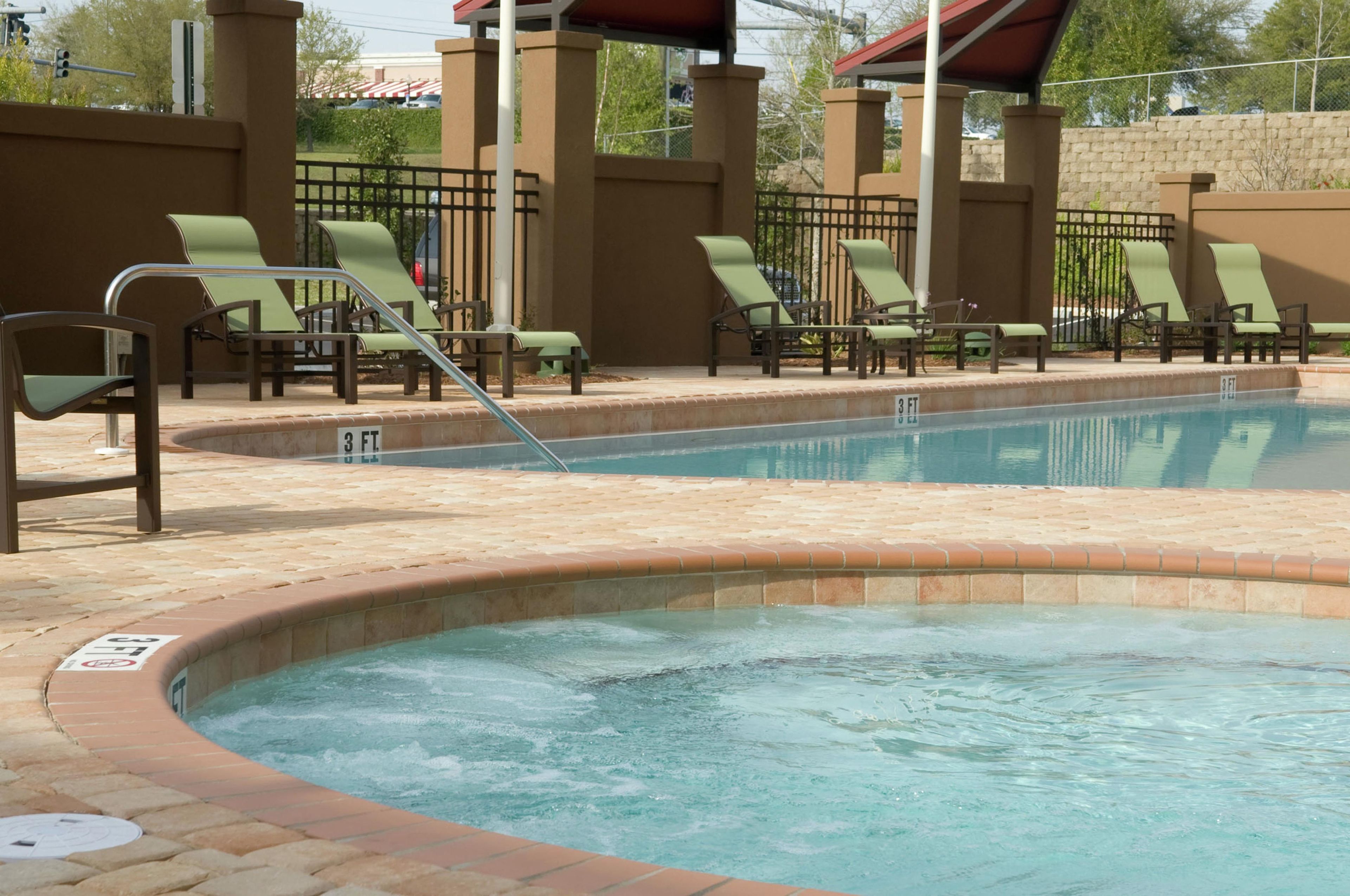 Una piscina con sillas de descanso y una zona de hidromasaje.