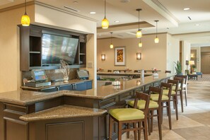 A hotel lobby with a reception desk, bar area, and seating. - Hilton Garden Inn Pensacola Airport - Medical Center (Pensacola)