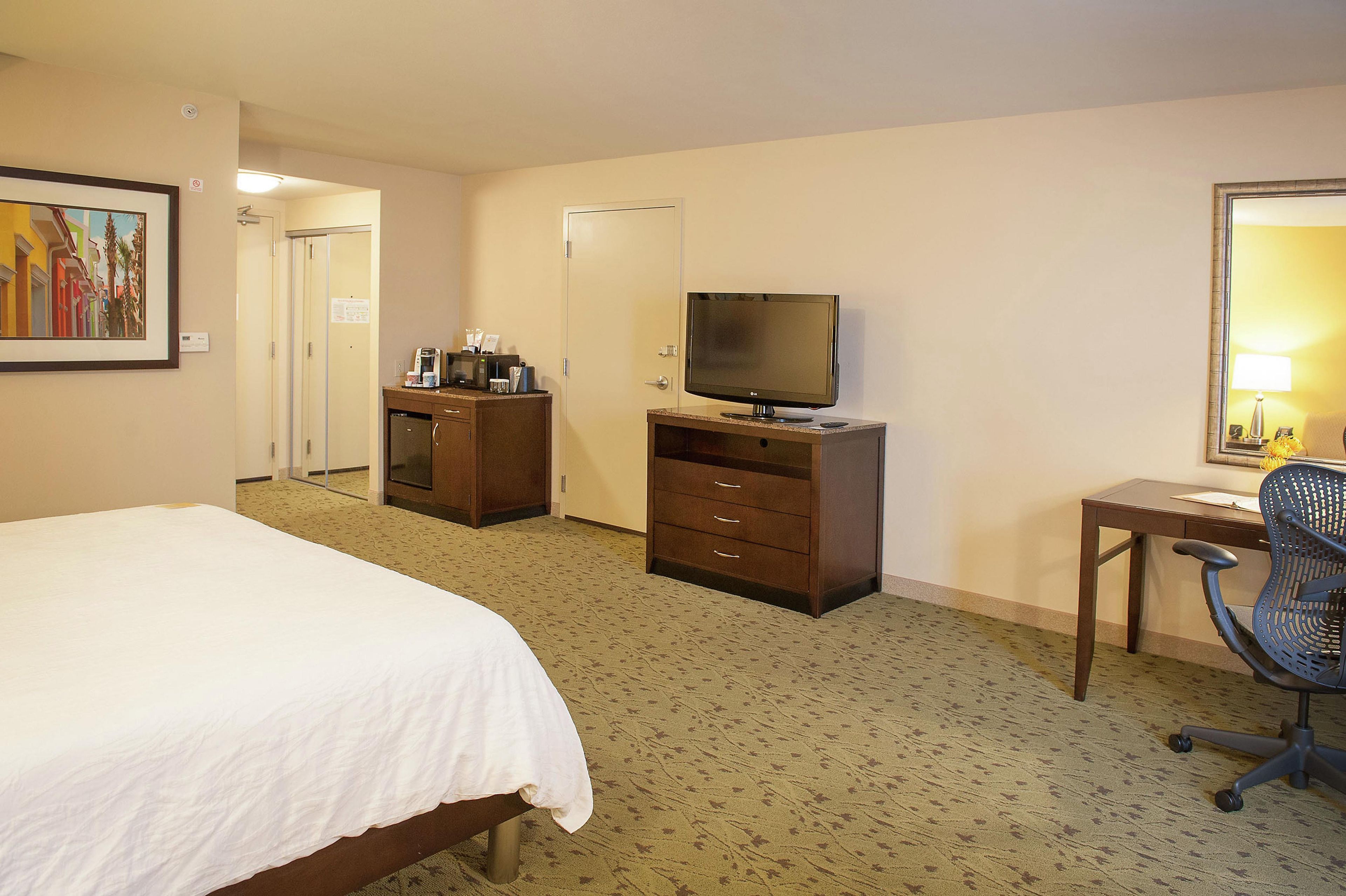 A hotel room with a bed, a desk, a television, and a chair.