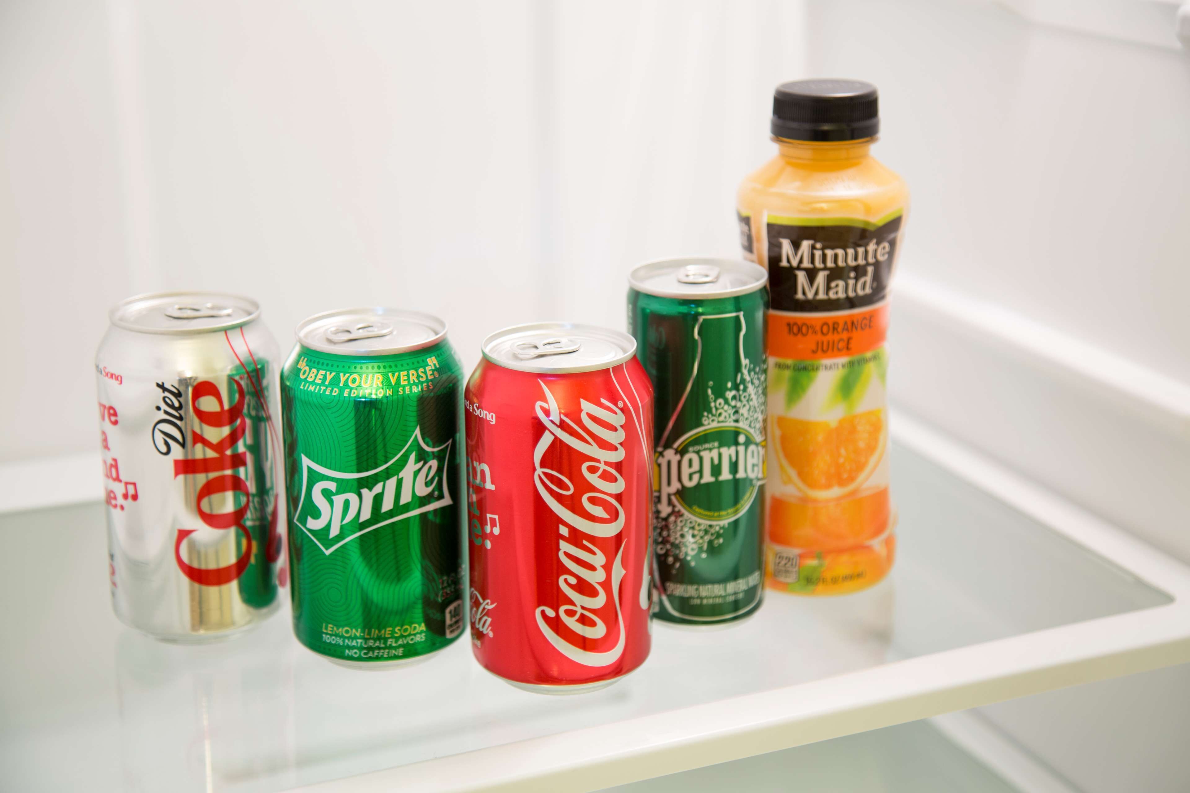 Un estante de nevera con seis latas de bebida y una botella.