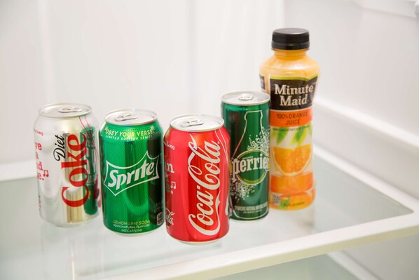 A refrigerator shelf with six beverage cans and a bottle.