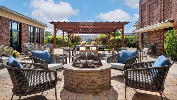 Un patio con mobiliario de mimbre, una chimenea y una pérgola.