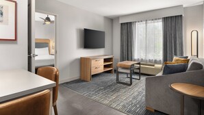 Una habitación de hotel moderna con cama, escritorio, silla, sofá y televisor.