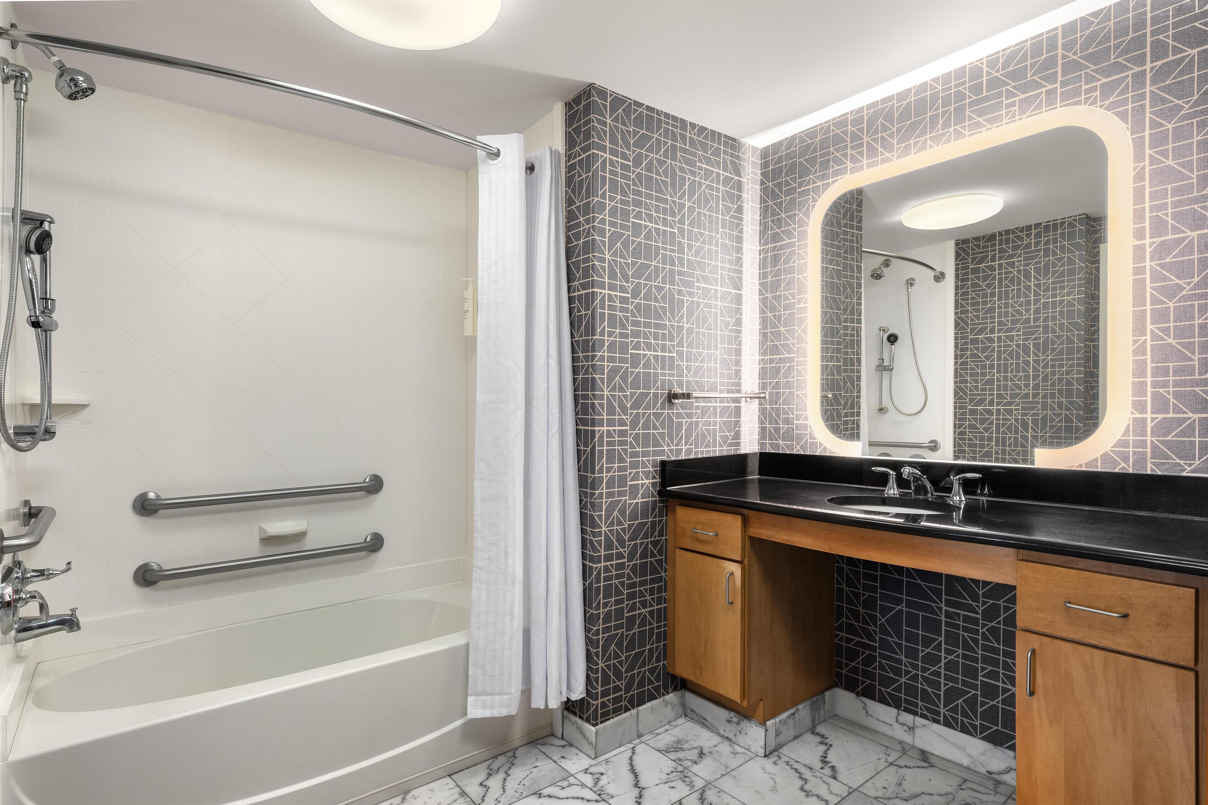 A modern bathroom with a walk-in shower, a bathtub, a vanity with a sink, and a large mirror.