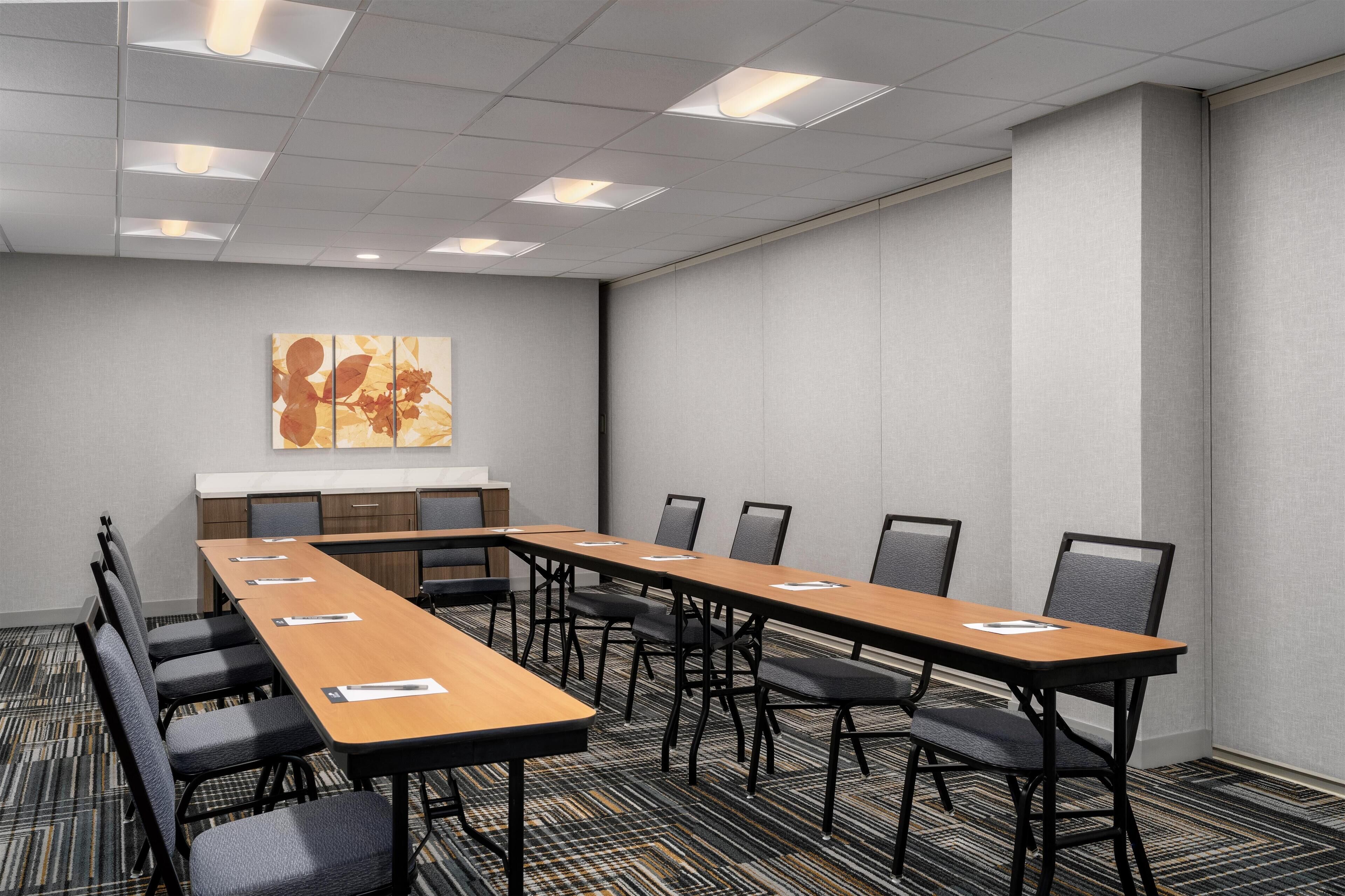 A conference room with a long table, chairs, a whiteboard, and a carpeted floor.