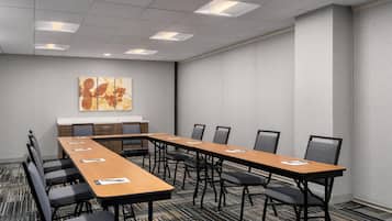 A conference room with a long table, chairs, a whiteboard, and a carpeted floor.