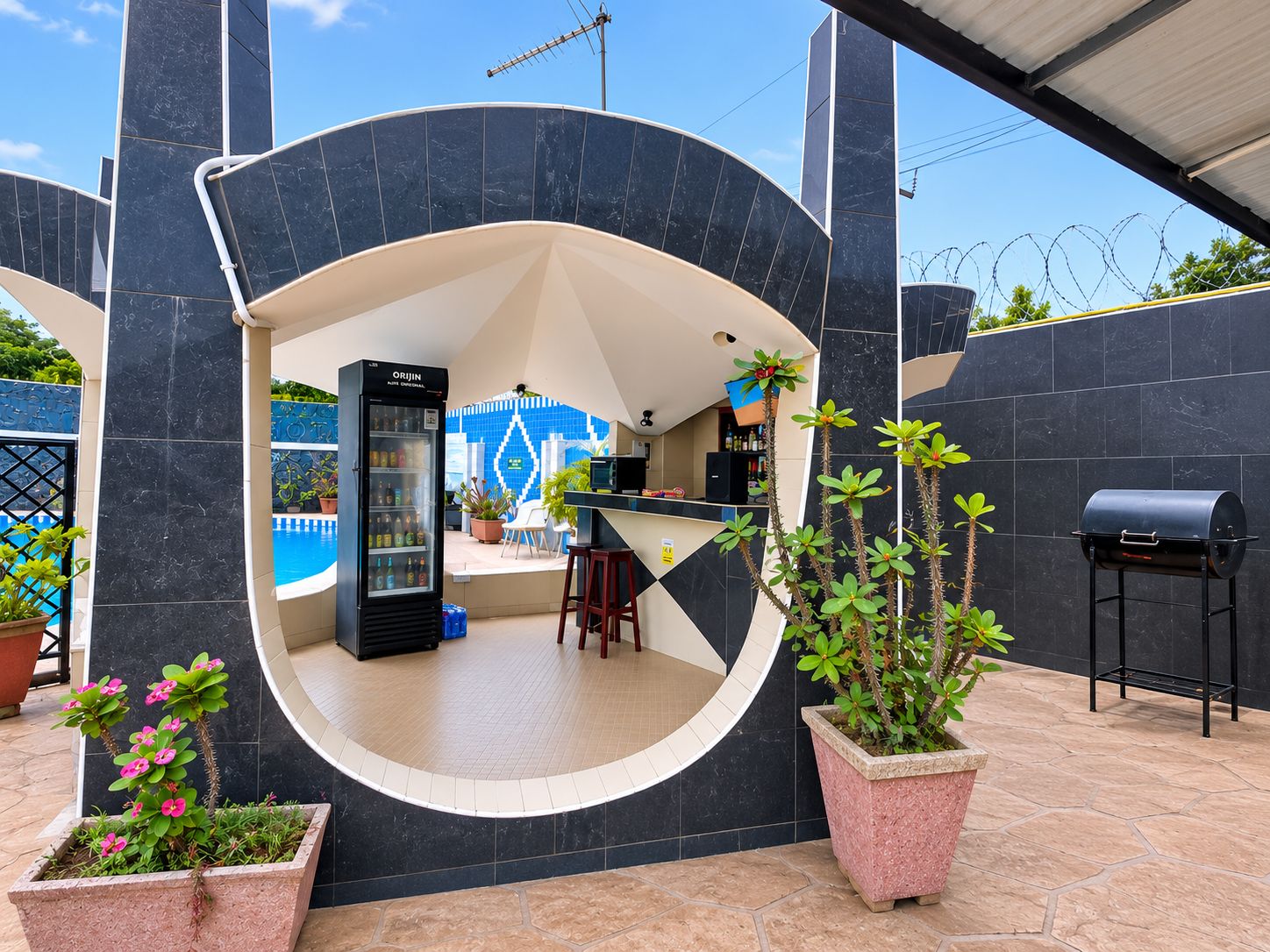A circular outdoor seating area with a bar, a refrigerator, and potted plants.