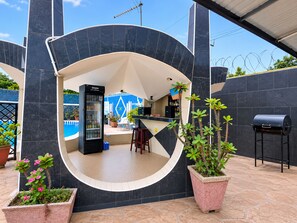 A circular outdoor seating area with a bar, a refrigerator, and potted plants. - Eastgate Hotel (Accra)