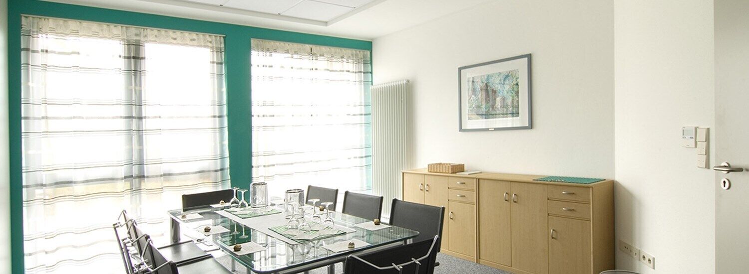 A conference room with a glass table, chairs, a cabinet, and a framed picture on the wall.