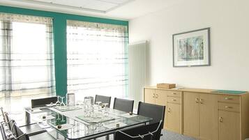 A conference room with a glass table, chairs, a cabinet, and a framed picture on the wall.