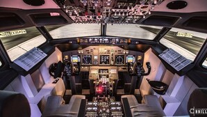 Het cockpit van een vliegtuig met meerdere bedieningspanelen, twee stoelen en bovenkastjes.