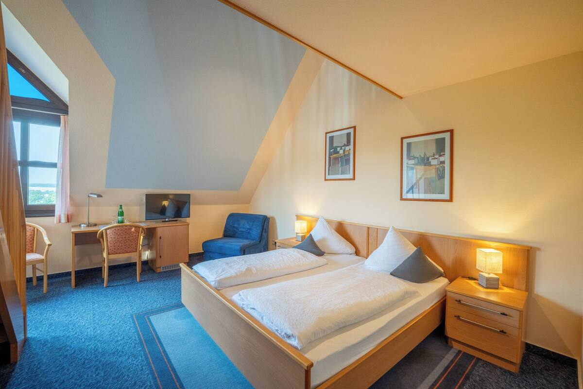Habitación de hotel con cama, escritorio, silla y televisor.