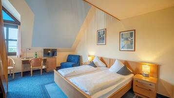 Ein Hotelzimmer mit Bett, Schreibtisch, Sessel und Fernseher.