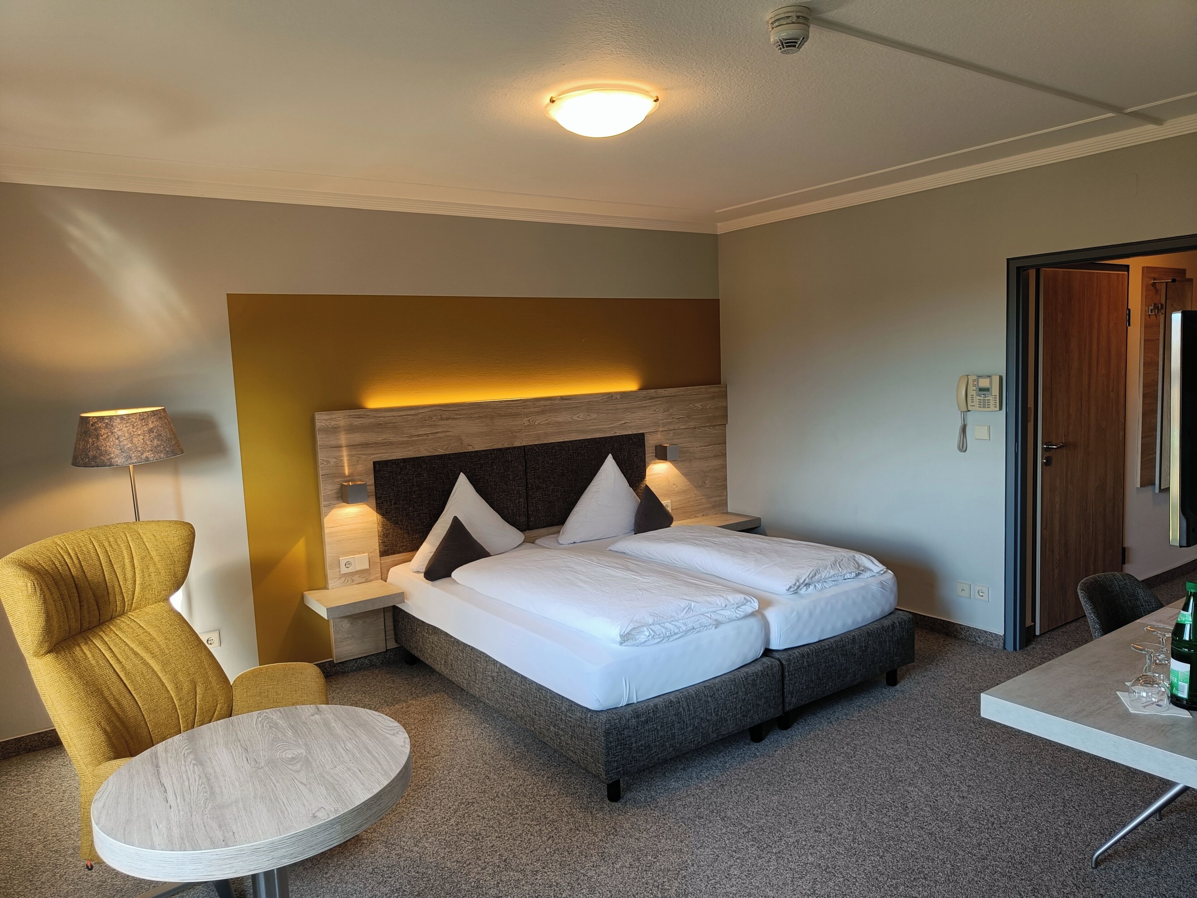 Ein Hotelzimmer mit Bett, Stuhl, kleinem Tisch und Schreibtisch.