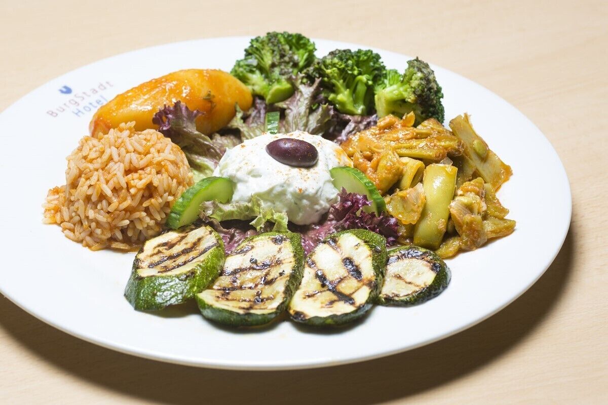 A plate of food with rice, grilled zucchini, broccoli, and a dollop of sauce.