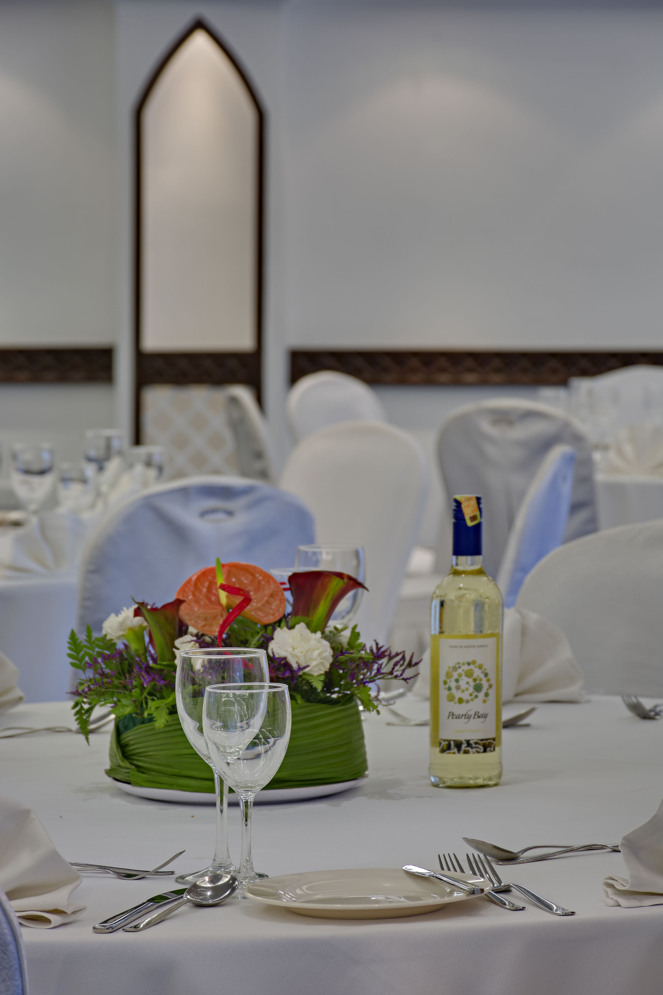 Ein Tisch, gedeckt für eine Mahlzeit, mit einer Weinflasche, einem Glas und einer Blumenarragemment.