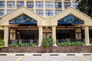 Fachada de hotel simétrica, con amplias ventanas y una entrada central flanqueada por dos paneles de vidrio decorativos.