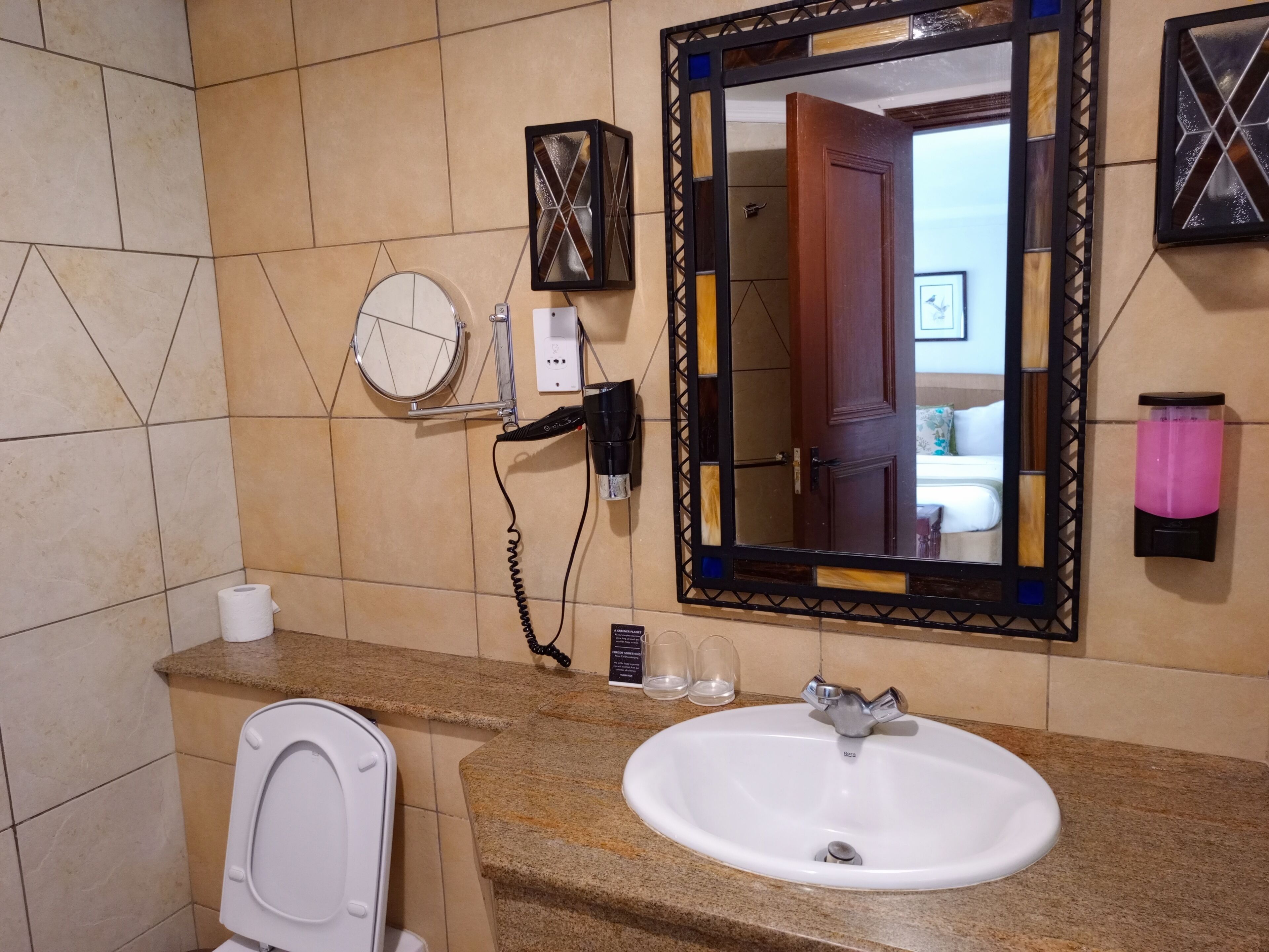 A bathroom with a white sink, a mirror, a hairdryer, and a toilet.