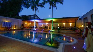 Una piscina interior con una fuente de agua, palmeras y una zona de bar con gente.