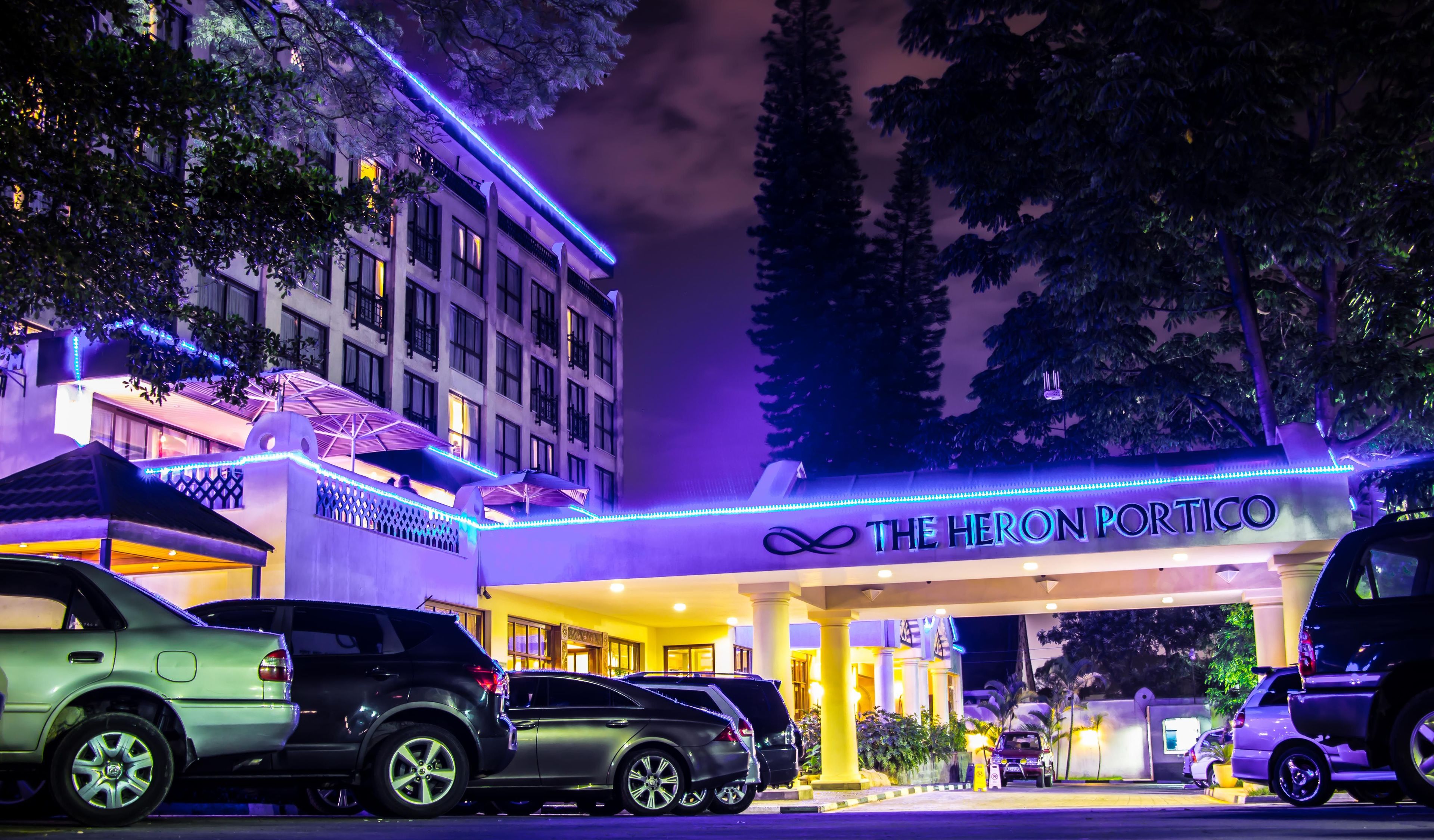 Ein Hotel namens "The Heron Portico" mit moderner Fassade und Parkplatz.