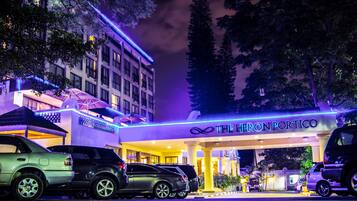 A hotel named "The Heron Portico" with a modern facade and a parking area.