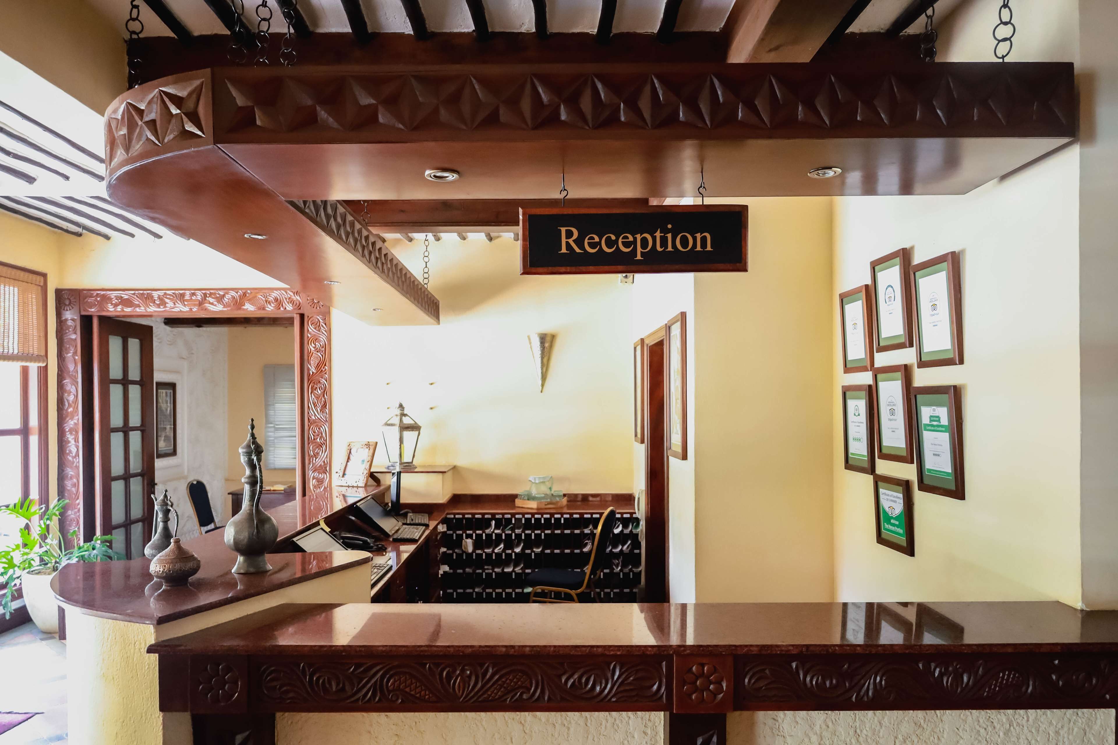 Un área de recepción con un mostrador de madera, un cartel que indica 'Reception' y certificados enmarcados en la pared.