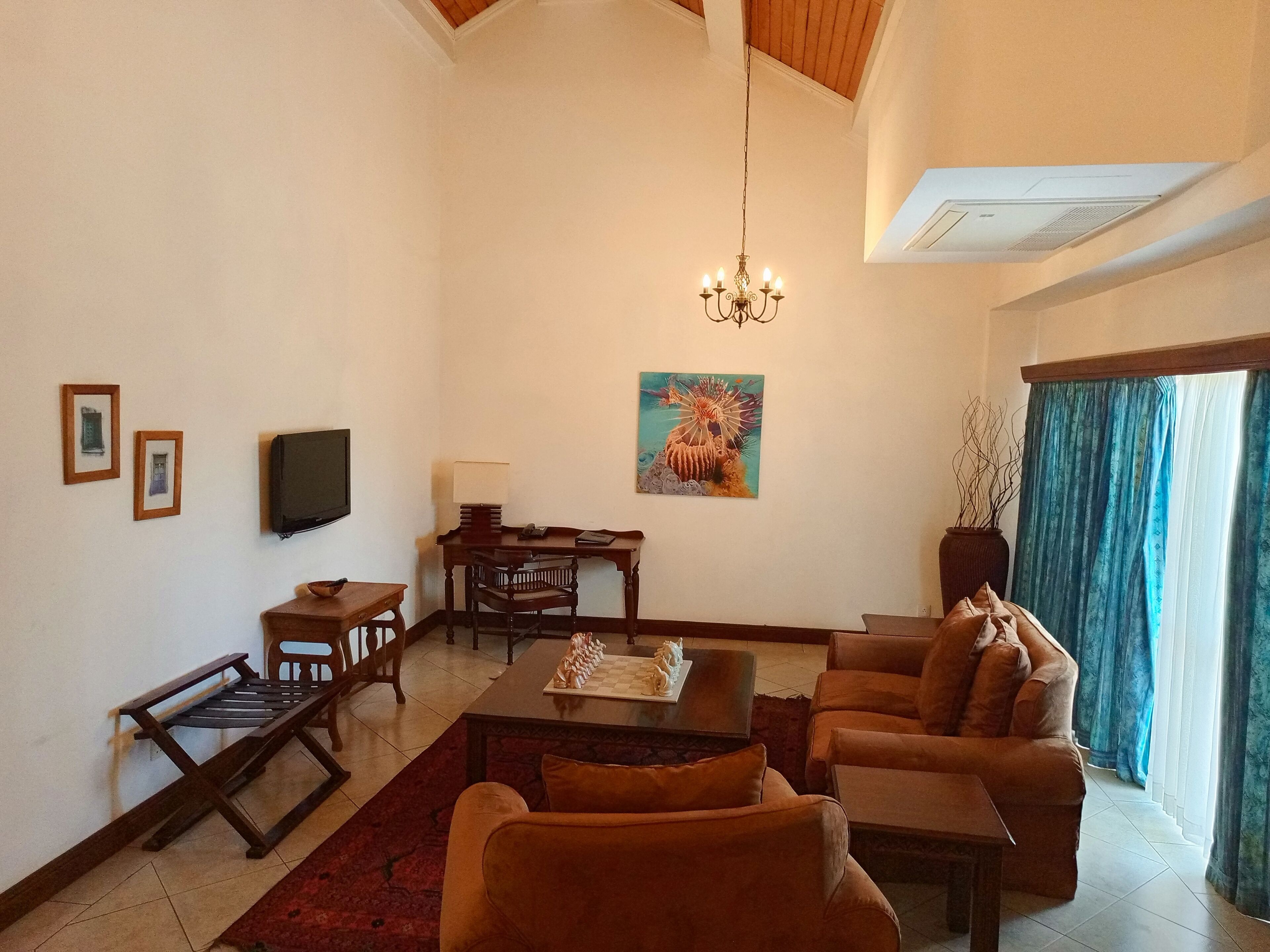A living room with a sofa set, a coffee table, a TV, and a painting on the wall.