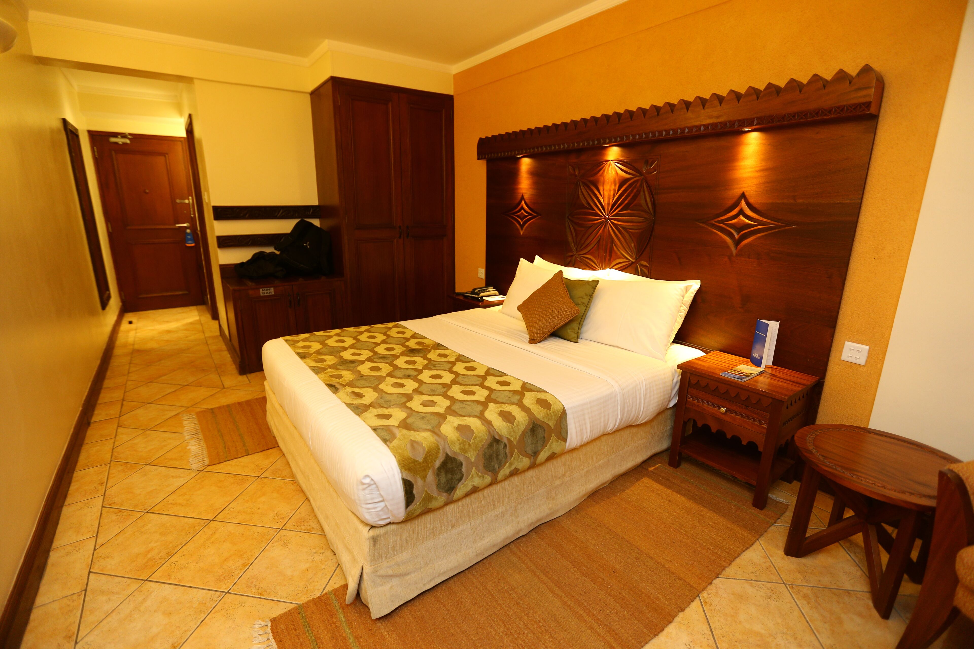 A hotel room with a large bed, wooden headboard, and a small wooden table.