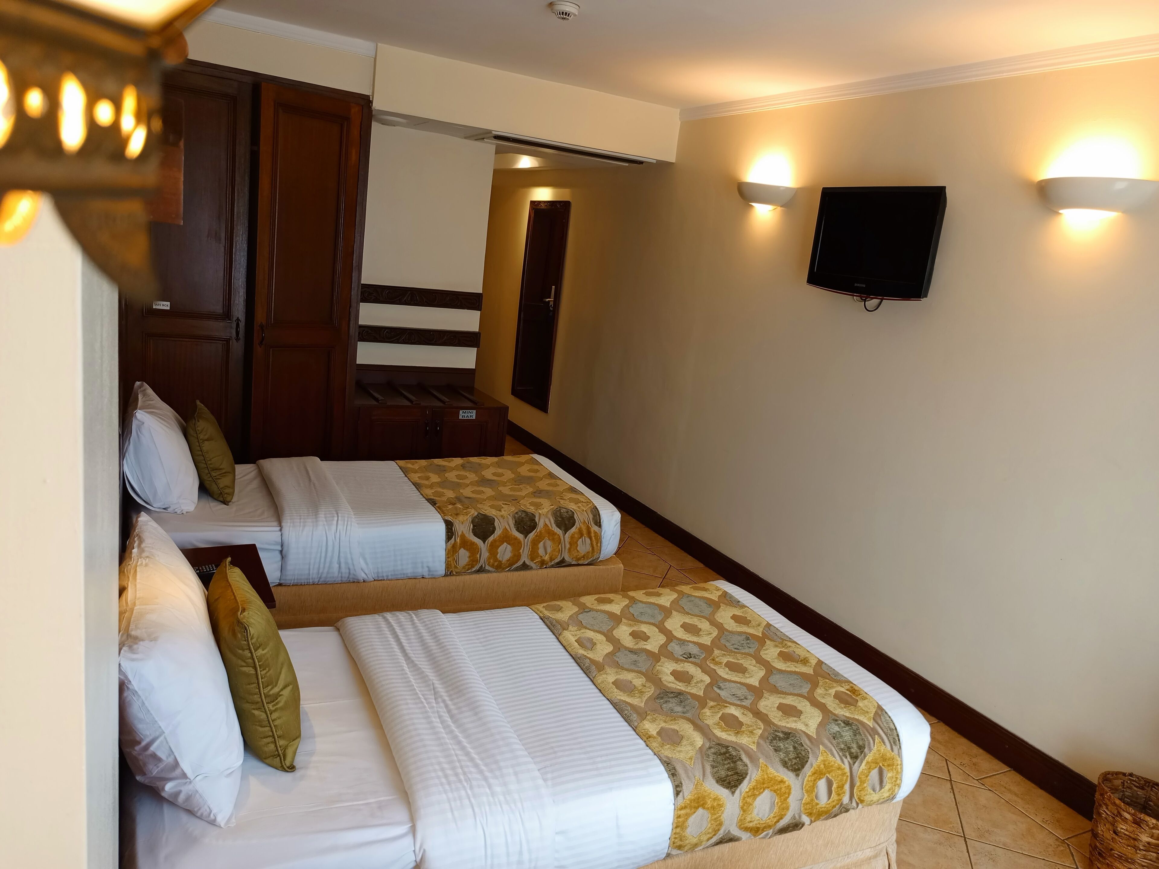 Ein Hotelzimmer mit zwei Betten, einem an der Wand montierten Fernseher und einer Treppe zu einem weiteren Raum.