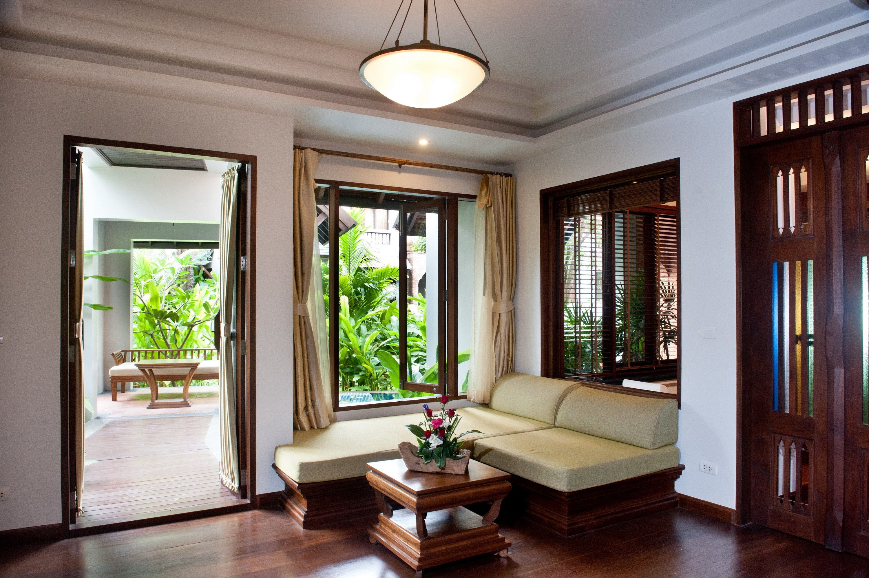 A room with a sofa, a wooden coffee table, and a view of greenery outside.