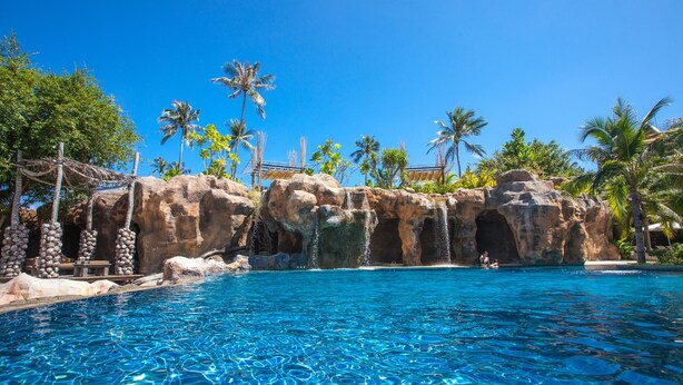A clear blue pool with a rocky waterfall feature, surrounded by palm trees and a tropical setting. - Royal Muang Samui Villas (Koh Samui)