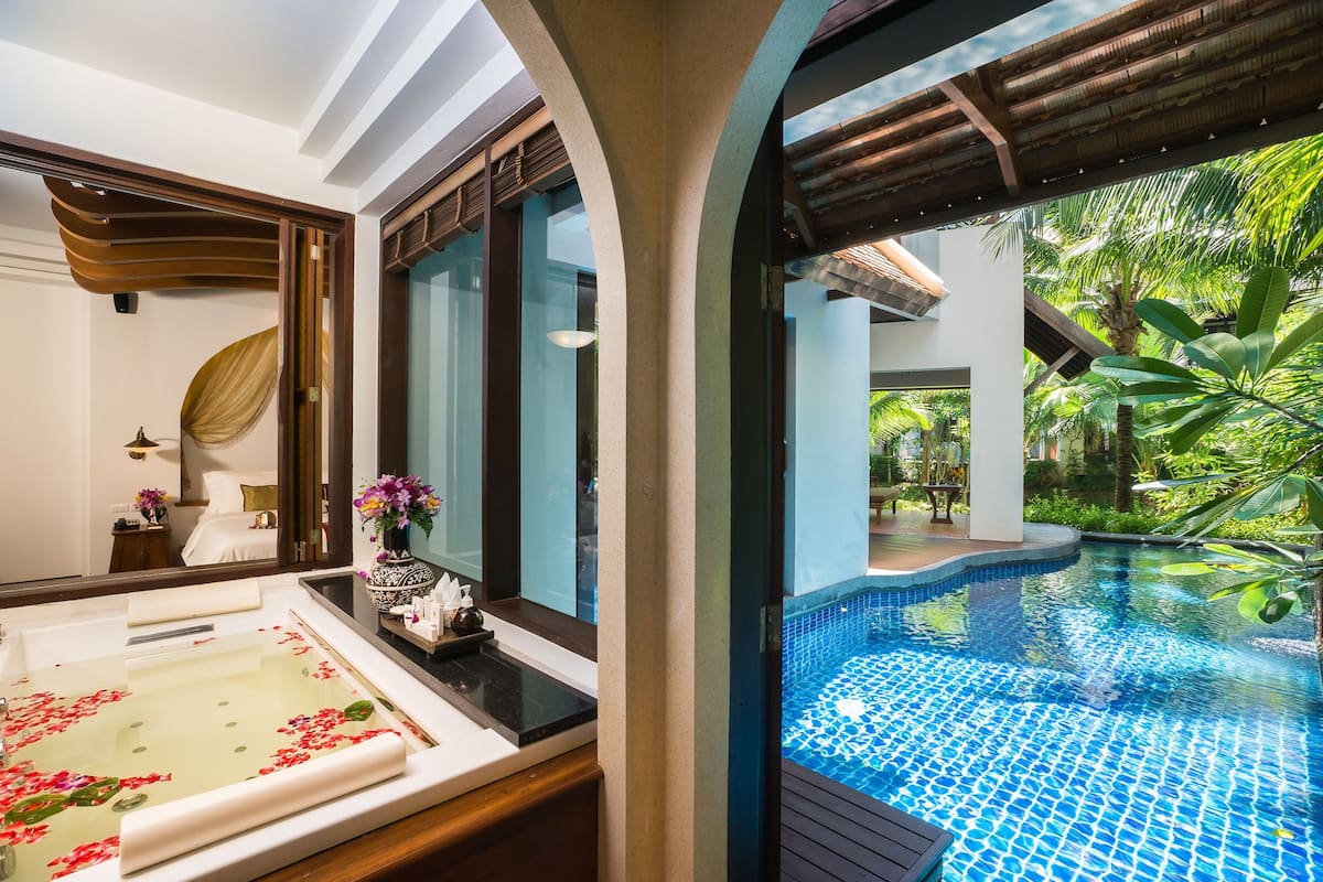 Um banheiro luxuoso com uma banheira grande, um espelho e vista para a área da piscina externa.