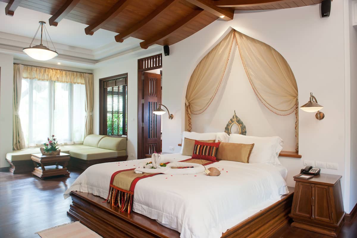 Um quarto espaçoso com uma cama grande, um espaço de estar e teto de madeira.
