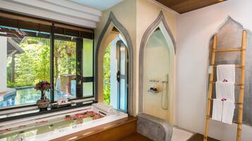 A bathroom with a bathtub, shower, and a view of a pool.