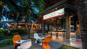 An outdoor seating area with modern chairs and tables, a covered patio, and a restaurant sign. - Royal Muang Samui Villas (Koh Samui)