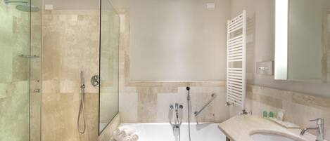 Un baño moderno con ducha de vidrio, bañera independiente y lavamanos con espejo.