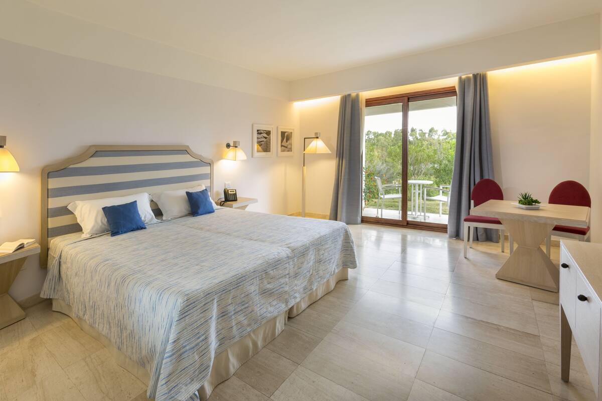 Een moderne hotelkamer met een groot bed, nachtkastjes, een bureau en een stoel.