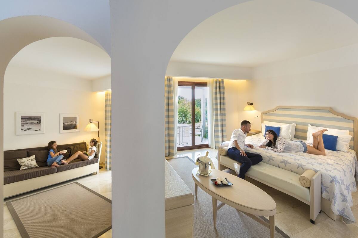 Een moderne hotelkamer met een bank, een bed, een tafel en uitzicht op de omgeving.