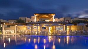 A hotel with a swimming pool, outdoor seating, and a covered patio area. - Resort Grande Baia (San Teodoro)
